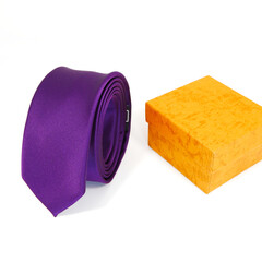 Purple tie rolled on white background with gift box together closeup view 