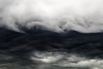 Naklejka premium Dark and Light Storm Clouds Forming Wave Patterns