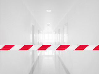 Red and white barrier tape has a background blurred image of the corridor