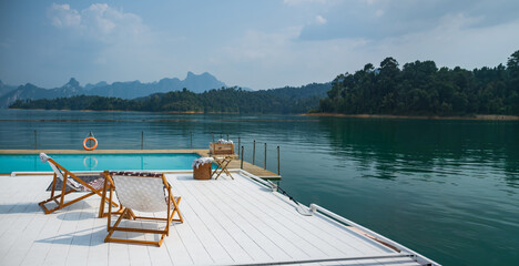 wooden beach chair and coffee table on white raft and swimming pool at waterfront of the open water...