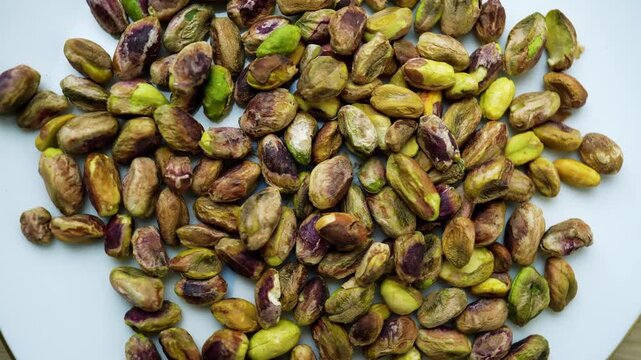 Unshelled Pistachios on White Surface, Close-up of unshelled pistachios on a white surface