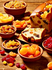Variety of Dried Fruits with Freshly Sliced Fruitcake on Rustic Wooden Table.Sweet Ingredients for Christmas baking