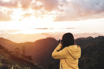 Young woman traveler taking a beautiful landscape at sunrise over the mountains, Travel lifestyle concept