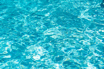 Water background. Blue water, ripples and highlights. Texture of water surface and tiled bottom.