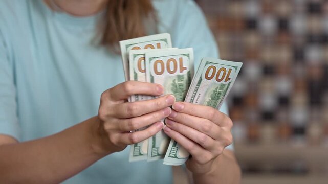 Female hands carefully counting one-hundred-dollar bills, calculating family budget expenses, saving money for high utility bills, or making a large cash payment for services