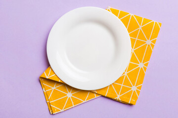 Top view on colored background empty round white plate on tablecloth for food. Empty dish on napkin with space for your design