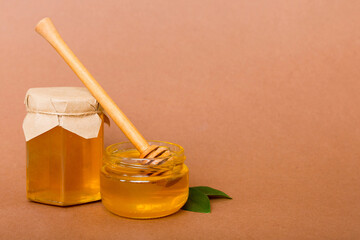 Honey in jar with leaves and honey dipper on colored background top view with copy text