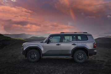 A silver off road SUV sits on a black sand and lava plain in Iceland, side profile and wide. Mossy...