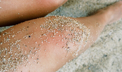 Sunlit grains hug a sun-kissed leg, crafting a sandy mosaic, evoking Caribbean Carnival vibes and...