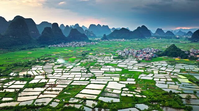 Aerial shot of the beautiful rural landscape with green farmland, villages, and spectacular karst mountain scenery in Guilin, China.
