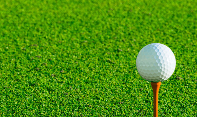 Golf ball on tee on golf course over a blurred green field.