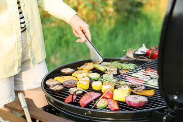 Vegetarian barbeque. Woman cooking vegetables on grill outdoors, closeup