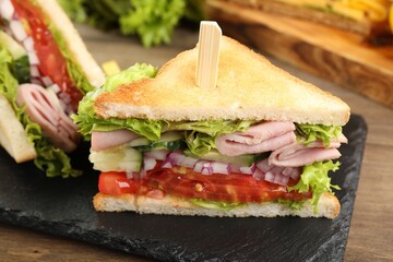 Tasty sandwiches with ham and vegetables on wooden table, closeup
