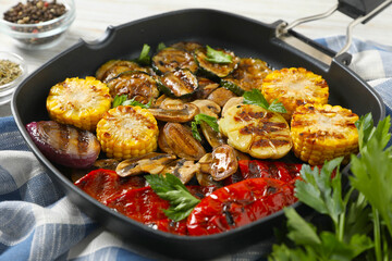 Delicious grilled vegetables with mushrooms in pan and spices on table, closeup