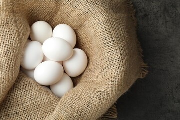 Many raw chicken eggs in sack on grey table, top view
