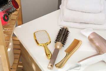 Different hair styling tools on white table in bathroom, closeup