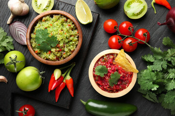 Tasty salsa in bowl and ingredients on black table, flat lay