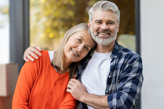 Older man and woman relaxing together at their new house entrance