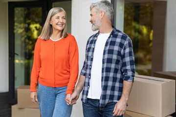 Couple standing on porch holding hands with boxes on background