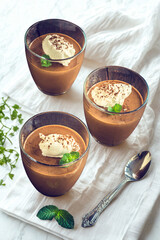 Three rich chocolate mousse desserts with cream and garnish