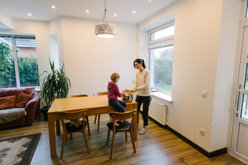 Woman cooking food indoors with a kid