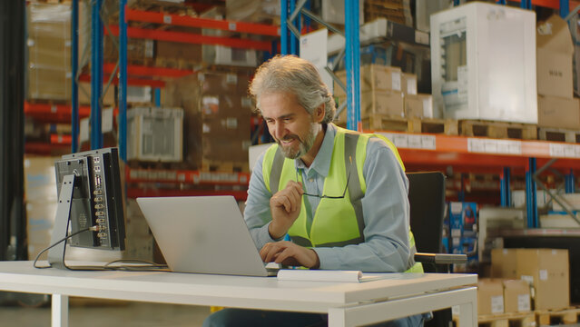 Senior warehouse manager using laptop checking operations