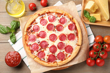 Delicious pepperoni pizza and ingredients on wooden table, flat lay