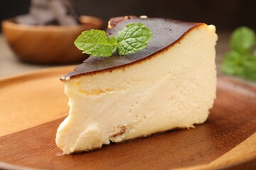 Piece of delicious Basque cheesecake with mint on table, closeup