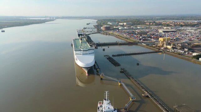 Huge industrial cargo freight ships and tankers docked at harbour on River Thames loading and unloading goods and products for international shipping, Tilbury, London United Kingdom