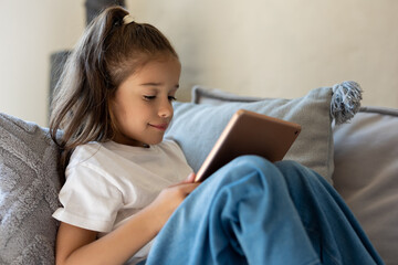 Girl using tablet for online learning in cozy home interior