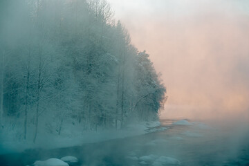 Misty winter river at sunrise with snow-covered trees and soft pastel light