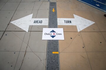 Overhead scene of painted crossroads with arrows and a card presenting a choice