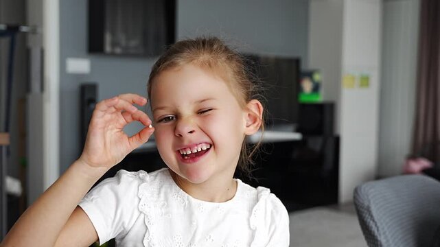 Smiling girl proudly shows her lost baby tooth, focus on joyful face. Celebration of childhood milestone and emotional development moment.