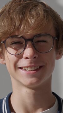Young male patient with poor eyesight putting on new glasses and smiling at the camera, a close-up portrait highlighting the importance of vision care and regular ophthalmology checkups