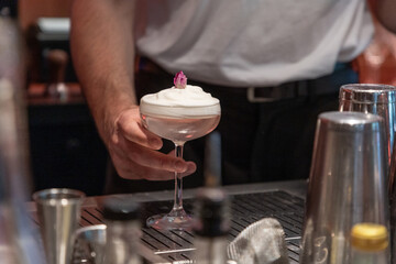 Bartender serving cocktail with whipped cream and decorative garnish