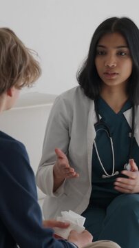 Female doctor shows empathy and explains medical advice to a distressed teenage boy in a hospital consultation, offering support and calm during an emotional visit