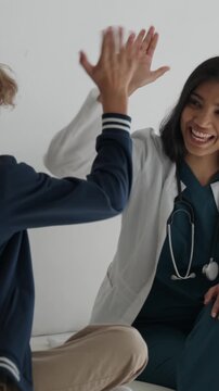 Kind pediatrician reassuring a young boy at a doctor's appointment, fostering a warm and caring environment before sharing a cheerful high five with him