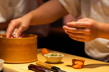 Skilled chef preparing sushi rolls with fresh ingredients in kitchen
