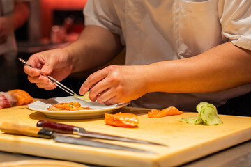Skilled chef preparing sushi with fresh ingredients on wooden cutting board