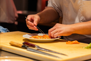 Obraz premium Chef preparing sushi with precision using chopsticks in a vibrant kitchen