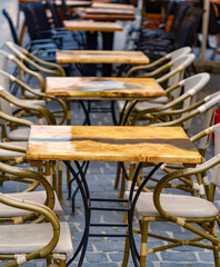 Outdoor cafe with empty wooden tables and chairs on the patio. Inviting relaxation and leisurely moments.