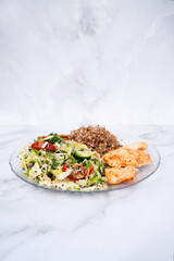 Fresh clean eating salad, chicken and buckwheat on glass plate on marble table
