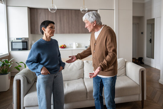 Upset mature couple fighting, man gesturing on disagreement. Marital strife, relationship struggle, angry confrontation, domestic conflict, misunderstanding of couple, family tension, argument issue