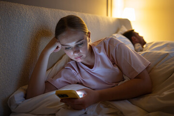Tired woman scrolling smartphone late unable to disconnect from web feed before rest. Nighttime procrastination with device, insomnia, social media addiction, exhausted female in mental fatigue
