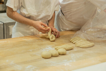 Young bakers shaping dough on wooden countertop kitchen environment