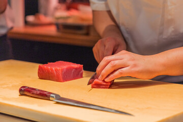 Chef slicing fresh tuna fillet on wooden cutting board in kitchen