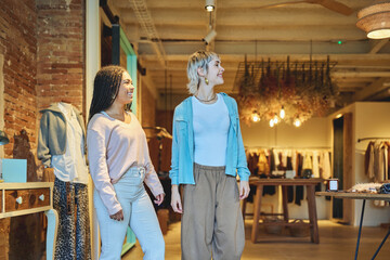 Two young women smiling while shopping in stylish boutique