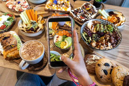 Person taking smartphone photo of healthy brunch food
