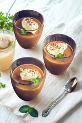 Three bowls of rich creamy chocolate mousse topped with whipped cream and mint
