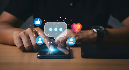 Man typing on a smartphone with glowing social media icons for comment, like, and heart over a dark background